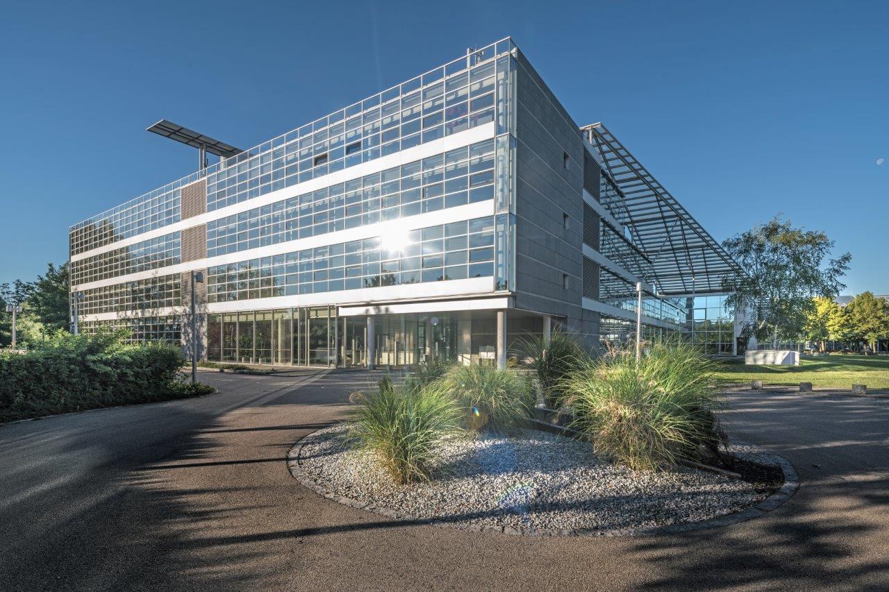 MABP building complex Hallbergmoos with glass façade, modern architectural design, green islands in the forecourt, sun reflections on windows, photo by Manfred Zentsch