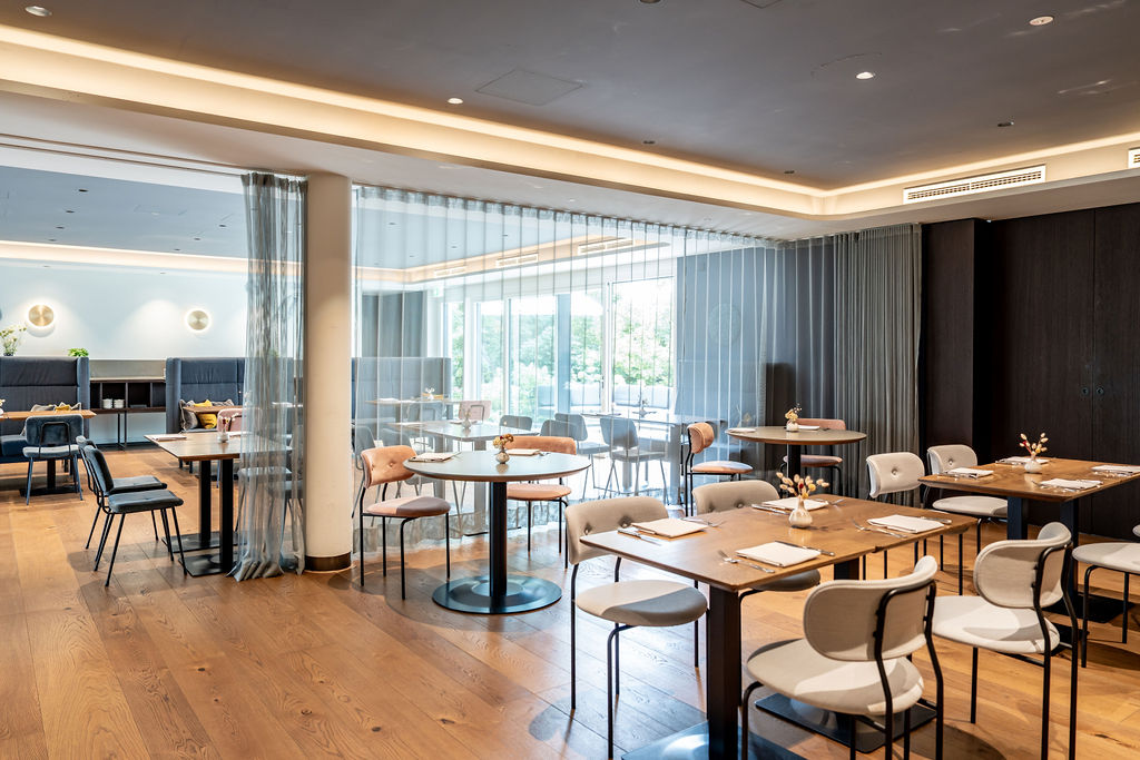 Moderne Restaurant-Innenansicht mit Tischen und Stühlen in neutralen Farben.