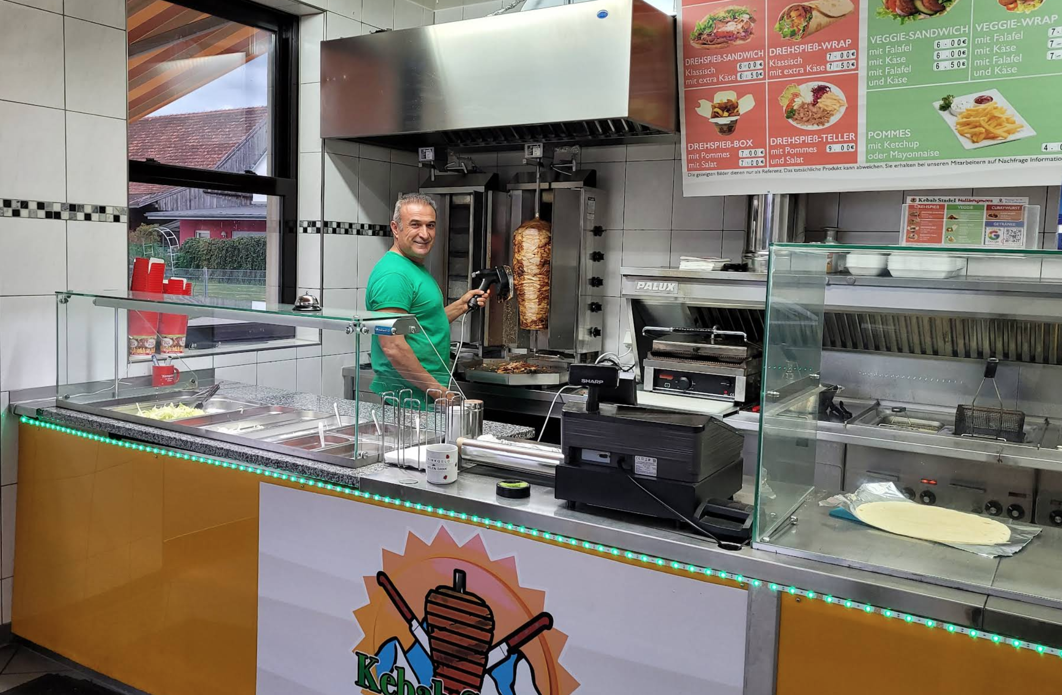 Koch im Kebabstadel, der frisches Fleisch am Drehspieß schneidet.