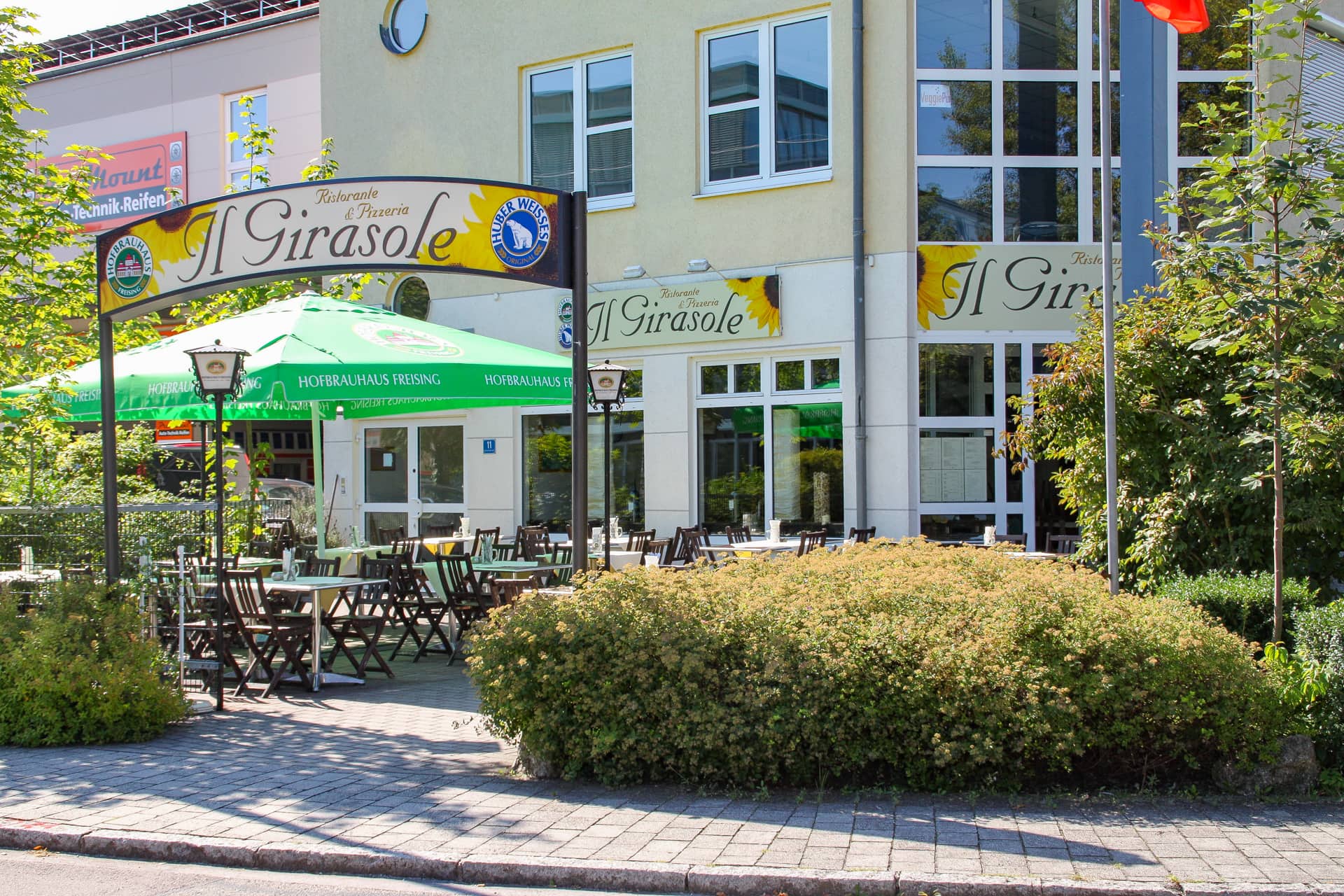 Restaurant Il Girasole in Hallbergmoos mit Außenbereich und Sonnenschirmen.