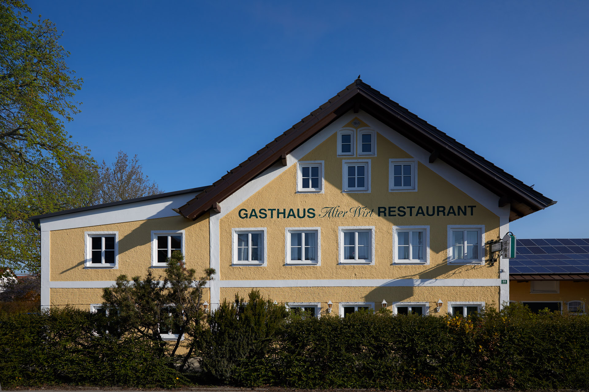 Gelbes Gebäude mit der Aufschrift 'GASTHAUS ALTER WIRT RESTAURANT' und mehreren Fenstern.