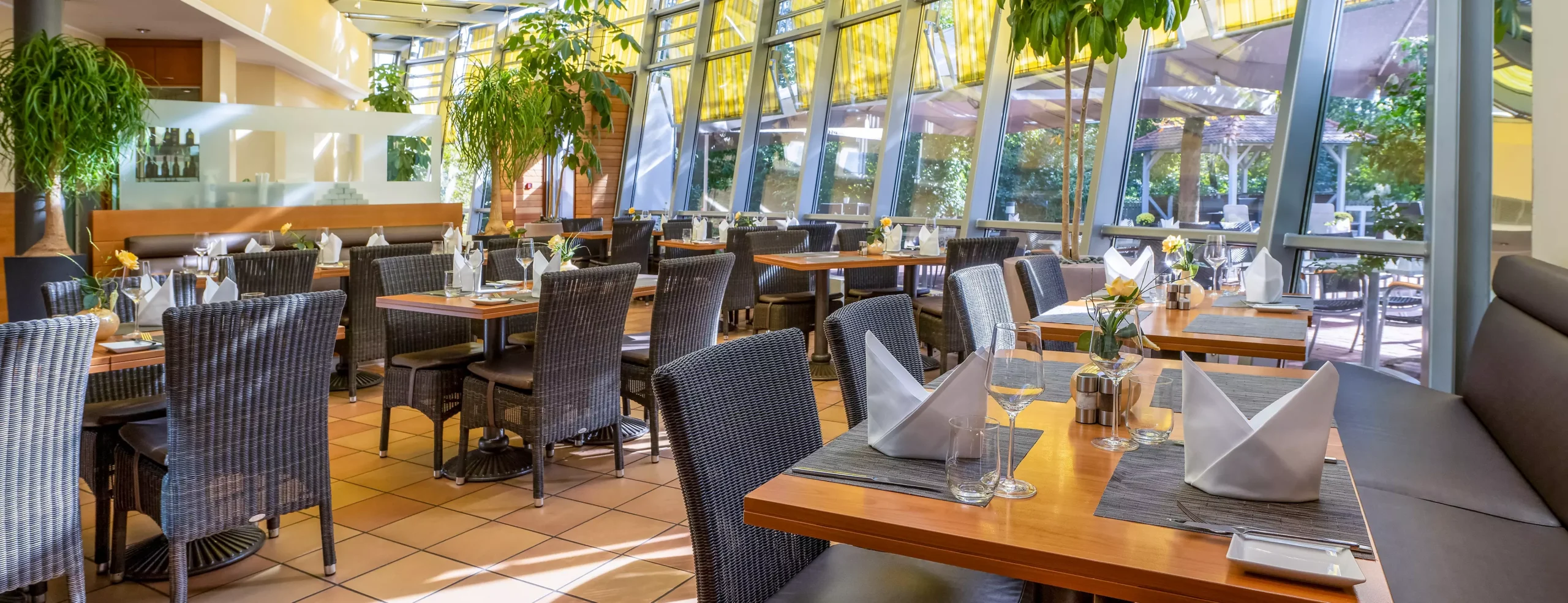 Innenansicht des Mövenpick Restaurants mit Tischen, Stühlen und Pflanzen.