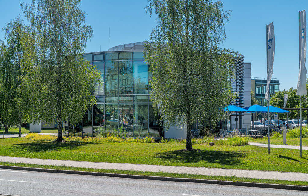 Moderne Bürogebäude mit großen Glasfenstern und einem runden Design im Münchener Flughafen Business Park.