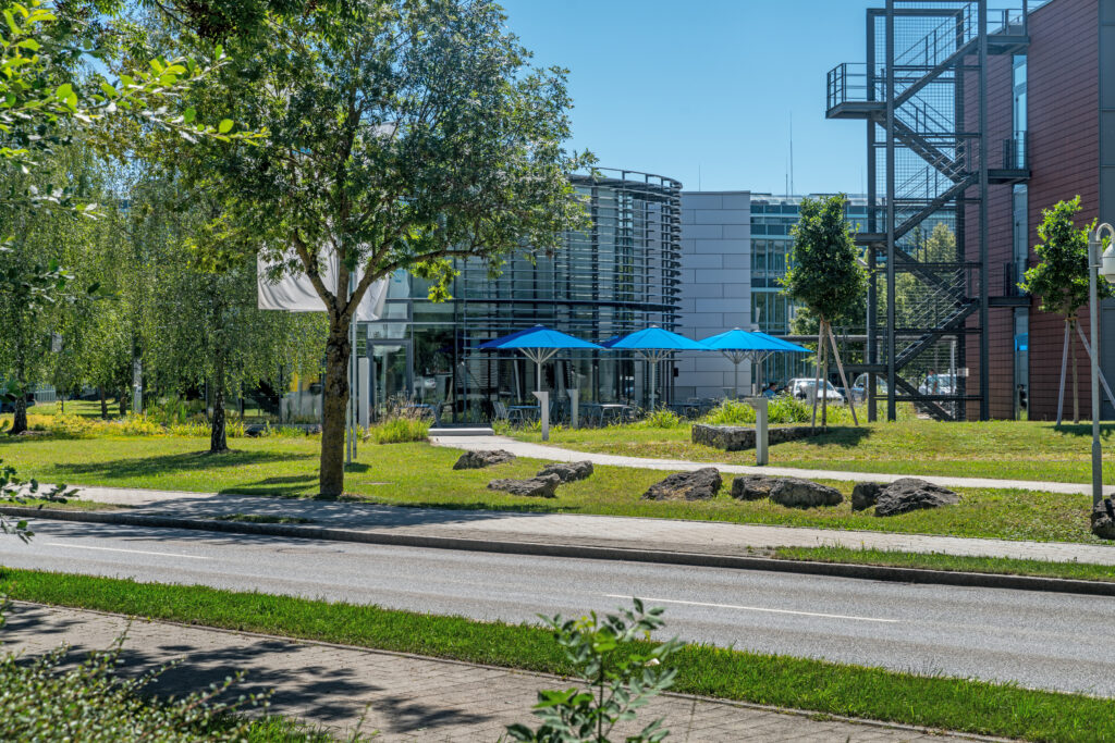 Moderne Gebäude mit blauen Sonnenschirmen in einem Außenbereich im Münchener Flughafen Business Park.