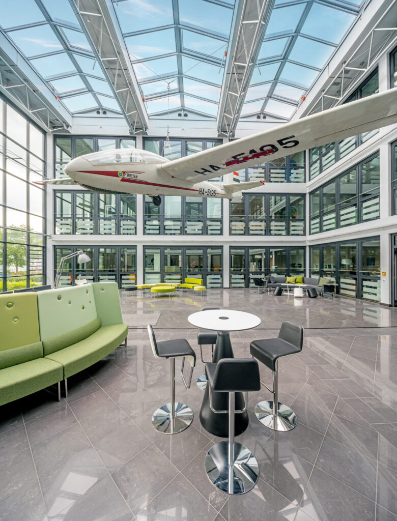 Ein Modellflugzeug hängt in einem modernen Innenraum mit großen Fenstern und stilvollen Möbeln.