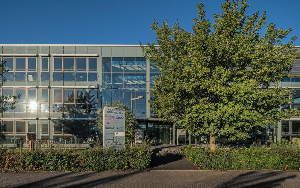 Moderne Bürogebäude mit Glasfassade und Beschilderung der DSV am Münchener Flughafen Business Park.