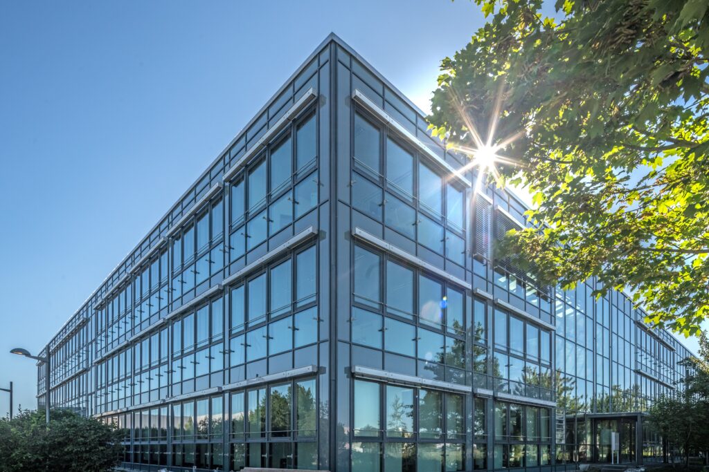 Moderne Bürogebäude mit Glasfassade und Sonnenschein in der Nähe des Münchener Flughafens.