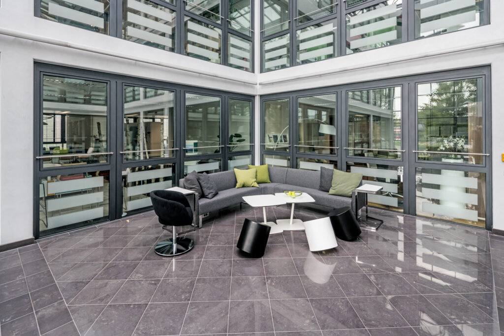 Moderne Sitzgruppe mit grauem Sofa und minimalistischen Tischen in einem hellen Raum.