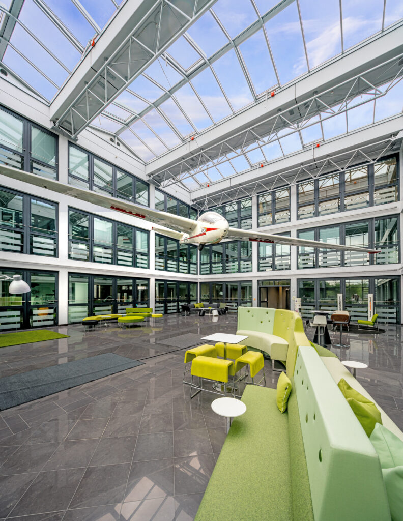 Ein moderner Innenraum mit einem hängenden Flugzeugmodell im MABP-Gebäude, das eine helle und offene Atmosphäre vermittelt.