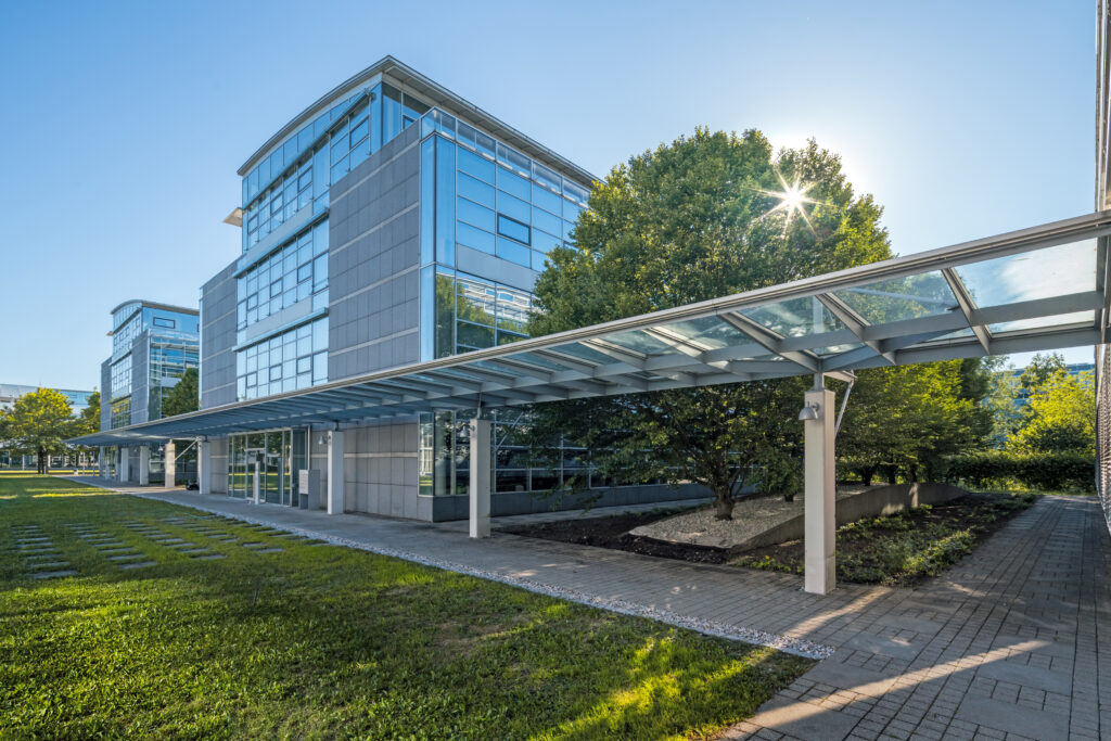 Moderne Bürogebäude mit Glasfassade und überdachtem Gehweg im Münchener Flughafen Business Park.