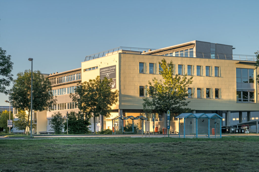 Das Lindbergh Center in München mit moderner Architektur und Bäumen im Vordergrund.