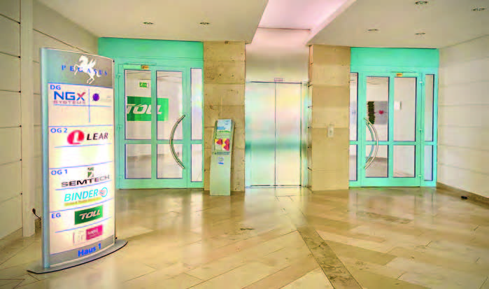 Eingangsbereich mit zwei Glastüren und einem Informationsstand im MABP.