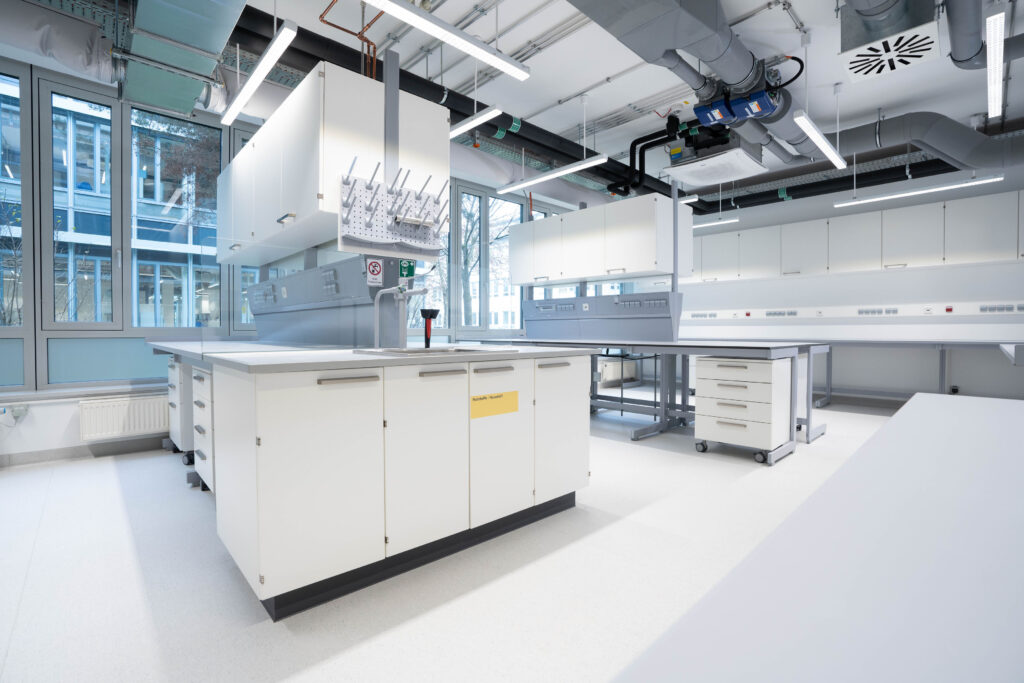 Moderne Laborumgebung mit weißen Arbeitsflächen und Geräten in einem gut beleuchteten Raum.