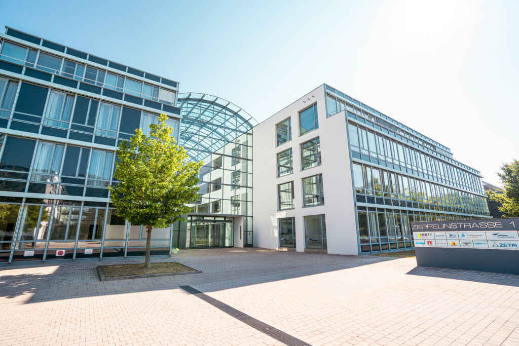 Moderne Architektur des Gebäudes an der Zeppelinstraße 1 mit großen Fenstern und Glasdach.