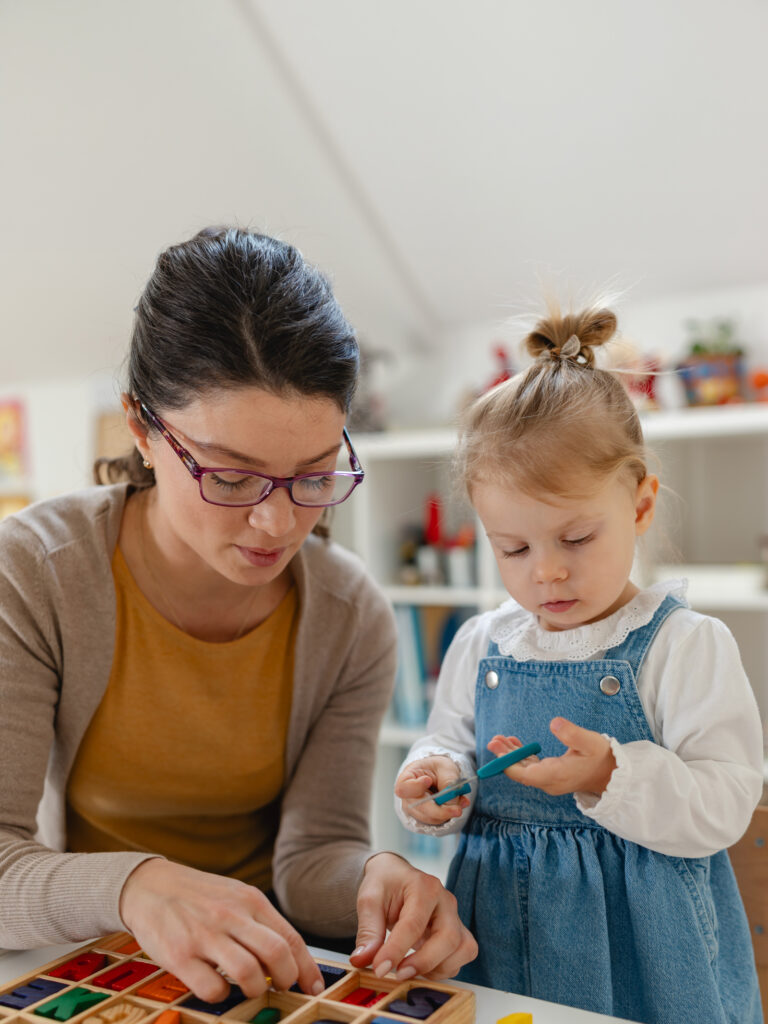 Eine Frau und ein kleines Mädchen arbeiten gemeinsam an einem Bastelprojekt mit bunten Materialien.