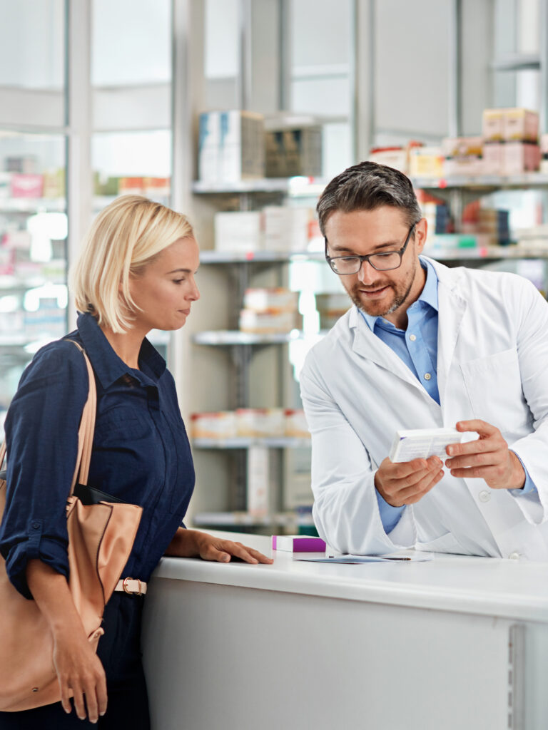 Ein Apotheker zeigt einer Kundin ein Medikament in einer modernen Apotheke.