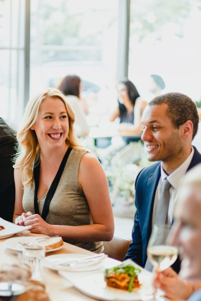 Lächelnde Frau und Mann bei einem Essen in einem Restaurant, beide in eleganter Kleidung.