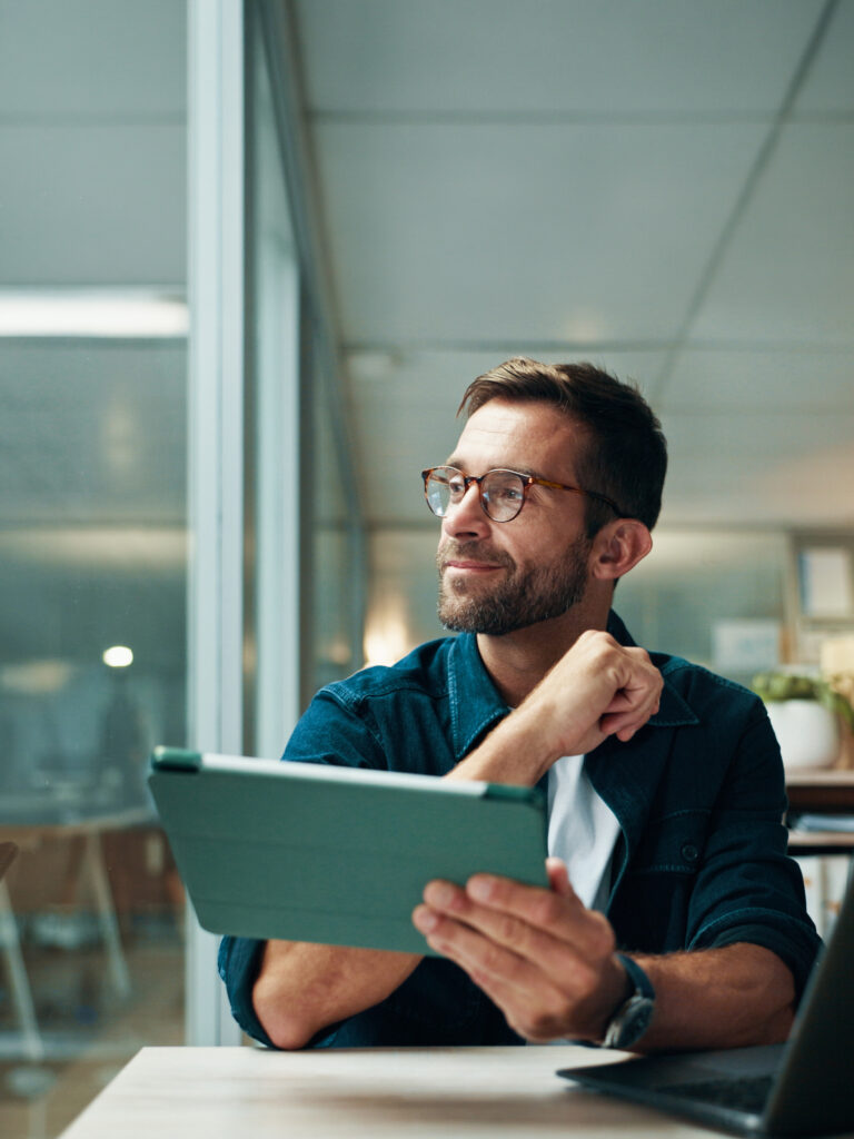 Mann mit Brille, der ein Tablet in der Hand hält und nachdenklich schaut.